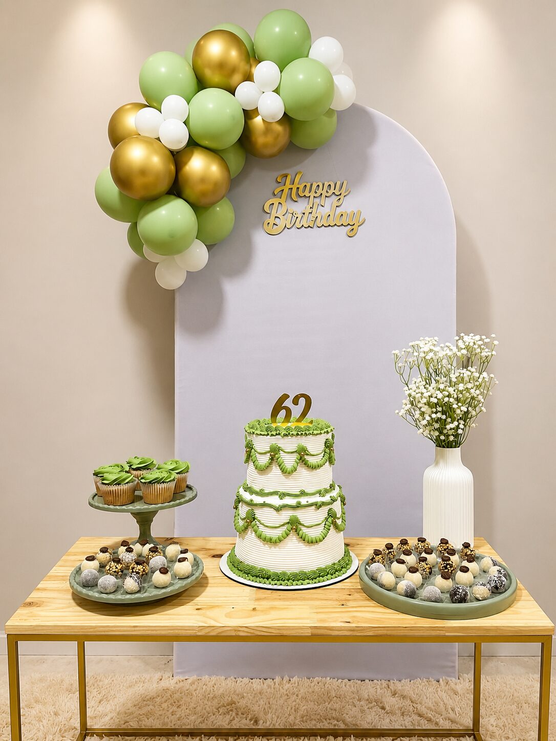 Mesa de festa com arco de balões verde e dourado
