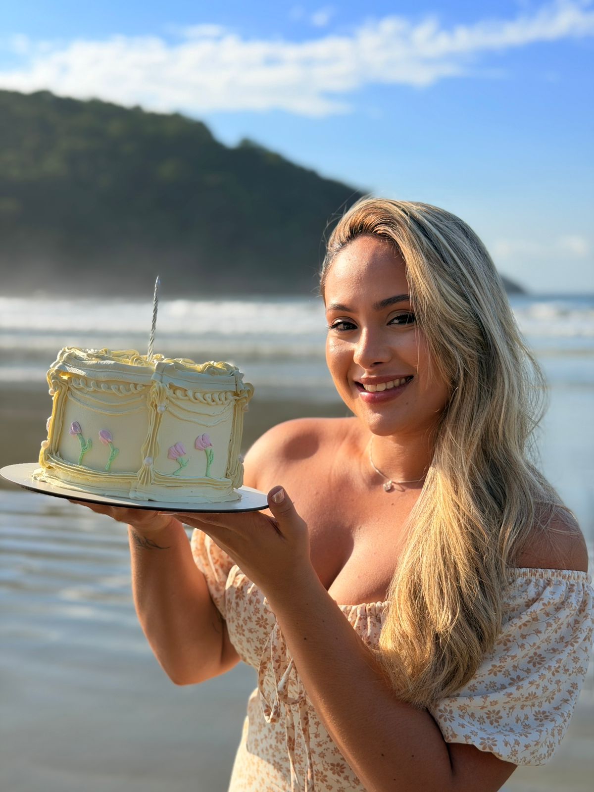 Confeiteira finalizando um bolo com flor de creme no ateliê